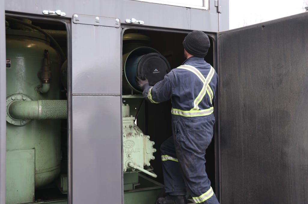 COMAIRCO technician performing preventive maintenance on an industrial air compressor system