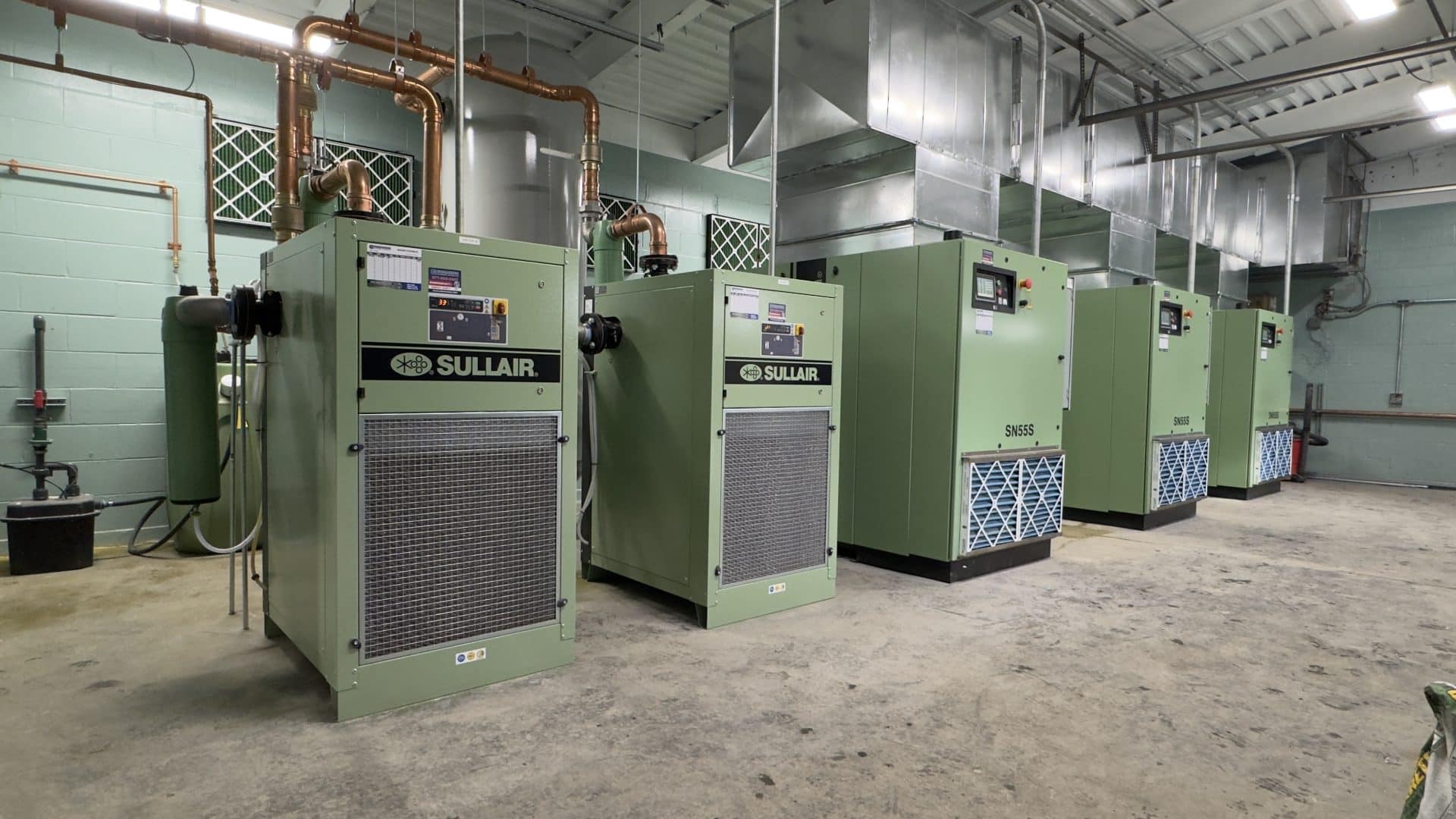 3 Sullair air compressors and 2 Sullair refrigerated air dryers with copper pipe for the air line and ductwork ventilating the heat out of the room